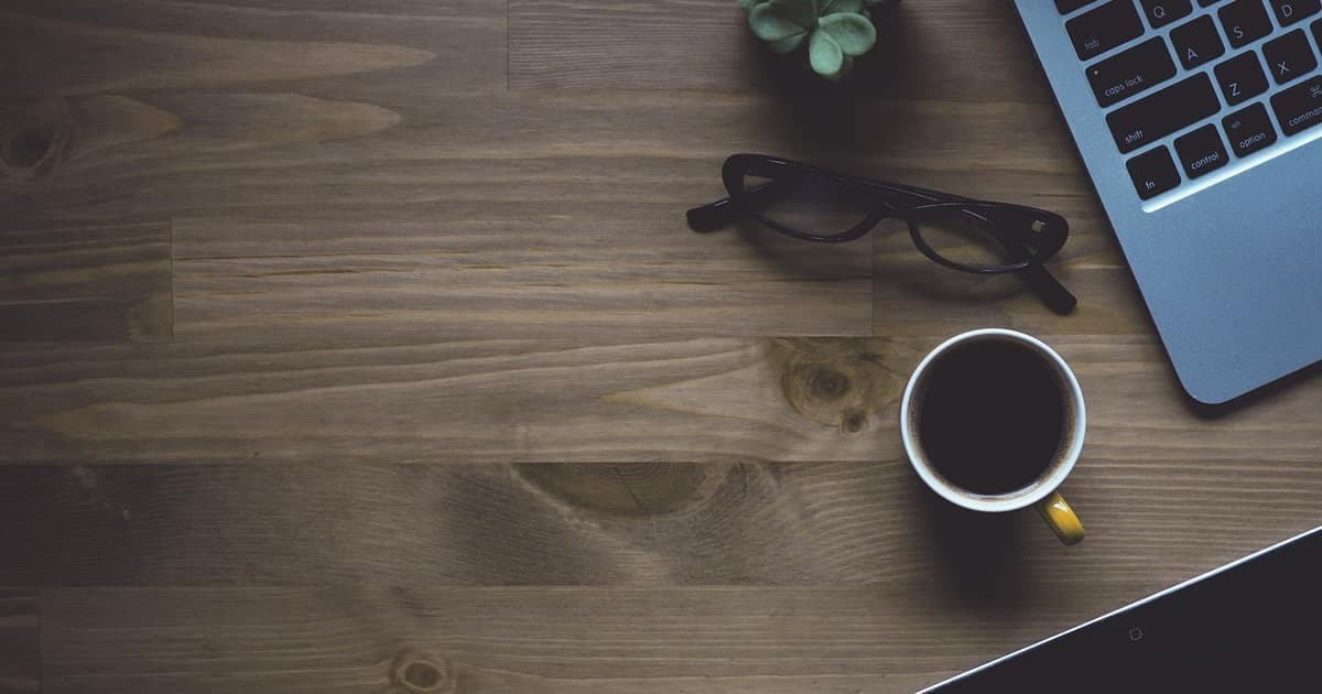 Workspace with laptop and coffee on a desk representing modern Trello alternatives for growing teams in 2026