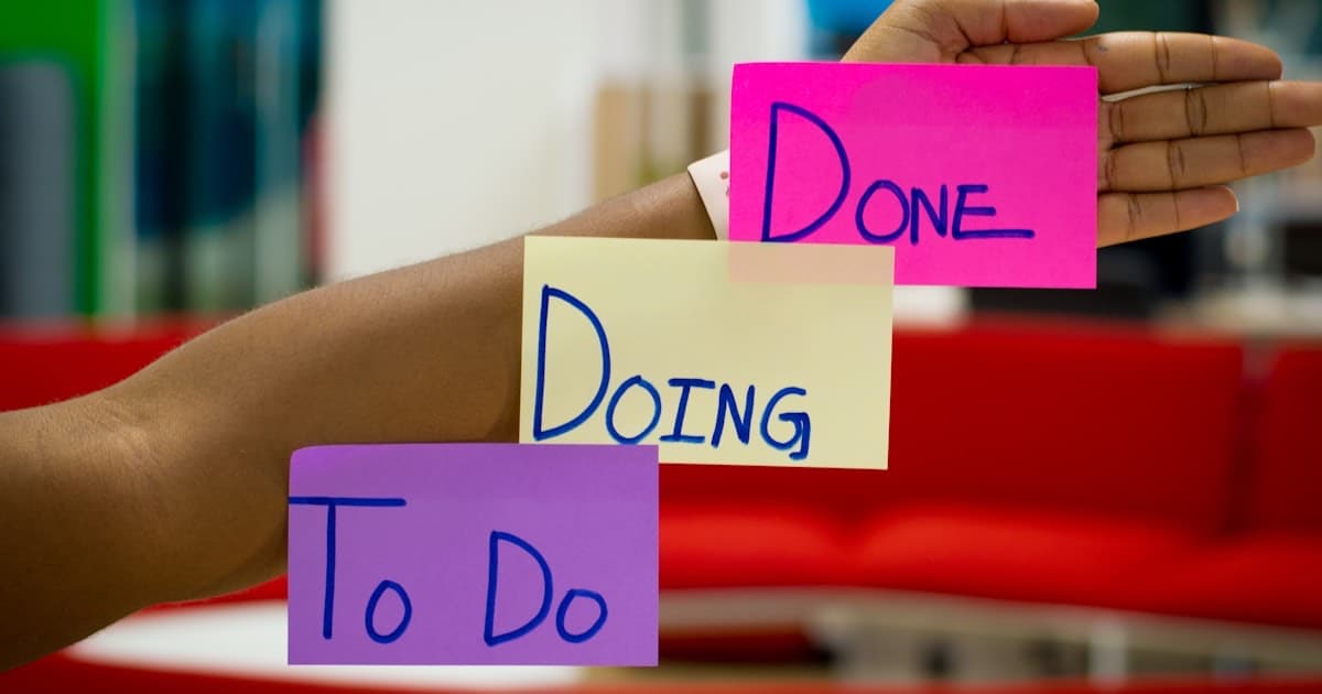 Hand holding To Do, Doing, Done sticky notes on an arm - representing the simple Kanban philosophy at the heart of the ClickUp vs Trello decision
