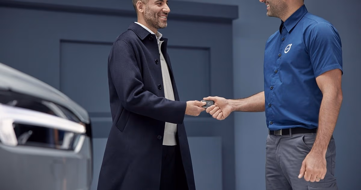 Car dealership salesperson showing a vehicle to a customer in a showroom